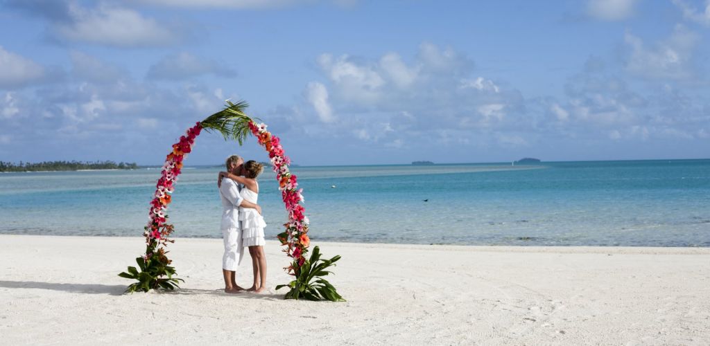 Heiraten Rarotonga - Paar unter Blumenbogen am Strand - Cook Inseln