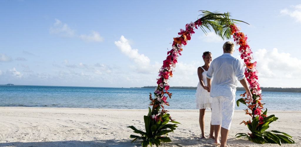 Heiraten Aitutaki - Paar unter Blumenbogen am Strand - Cook Inseln