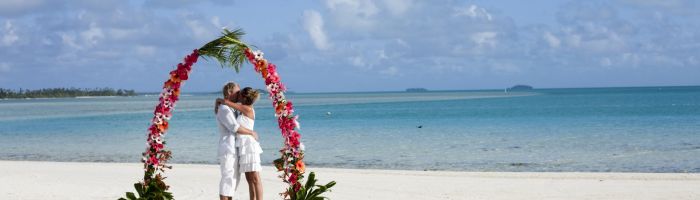 Heiraten Rarotonga - Paar unter Blumenbogen am Strand - Cook Inseln