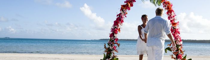 Heiraten Aitutaki - Paar unter Blumenbogen am Strand - Cook Inseln