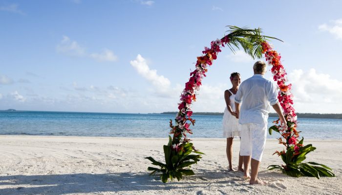 Heiraten Aitutaki - Paar unter Blumenbogen am Strand - Cook Inseln